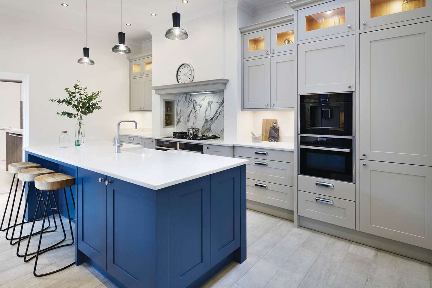 Light grey floor-to-ceiling Callerton kitchen cupboards, paired with blue kitchen island and white marble worktops