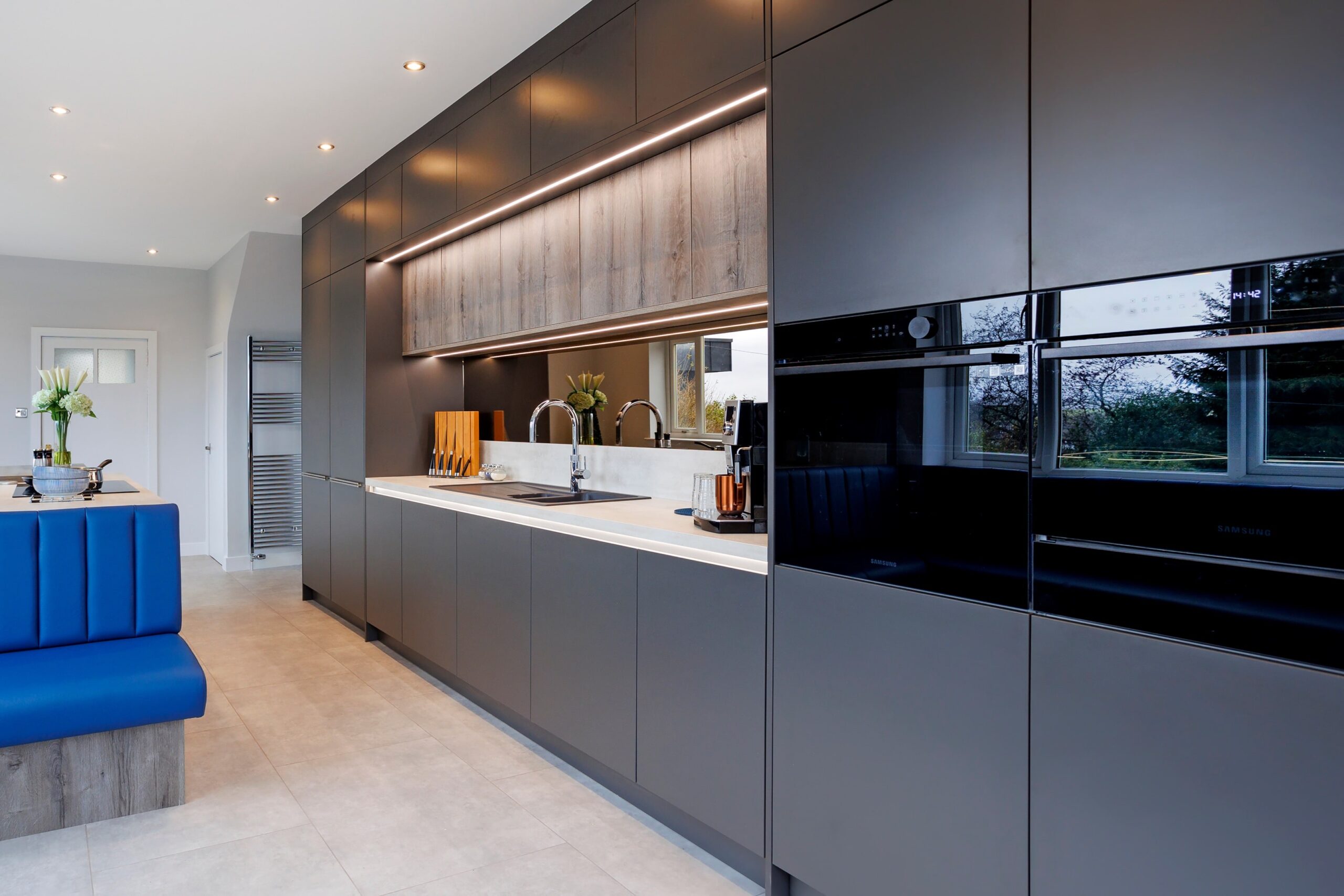 Grey kitchen cabinets featuring a white worktop space and integrated ovens